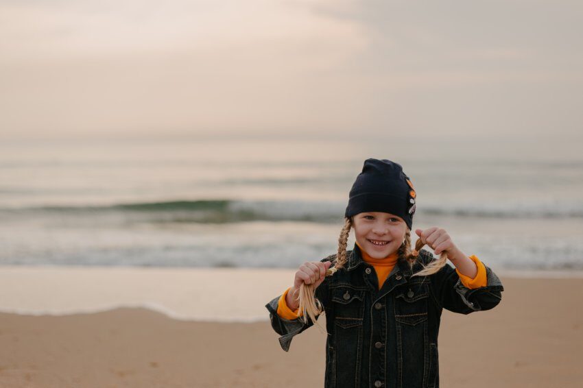 girl smiling on beach holding plaited hair, scotland