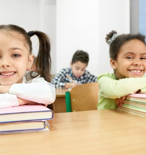 school withdrawal, two children beaming with smiles and sitting with books